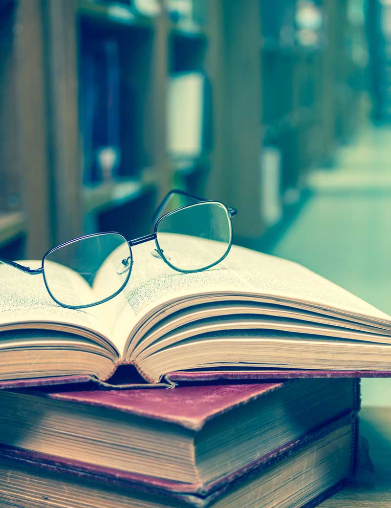 probate attorney massachusetts - Photo description: Glasses on the books in library with library blurred background.